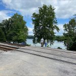 Two people walk along a road at a railroad crossing. In the background is the Ohio River.